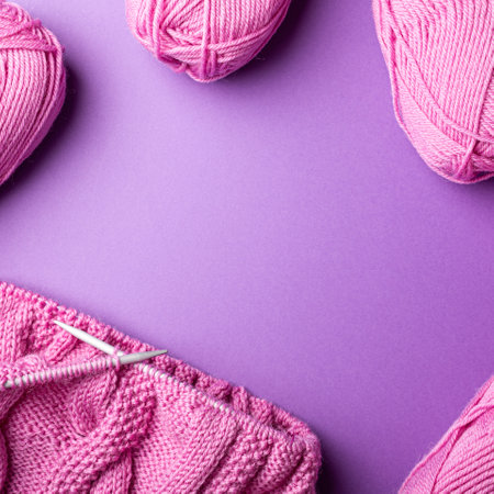 Knitting background with pink wool yarn over lilac, top view, flat lay with copy spaceの写真素材
