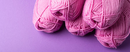 Banner with pink wool yarn over lilac, top view. Knitting background overhead shot with copy space