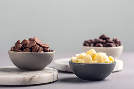 Ingredients for cooking hot chocolate. White, milk and dark chocolate chips Over gray background, copy spaceの写真素材