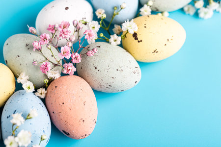 Easter composition with spring flowers and colorful quail eggs over blue background. Springtime and...