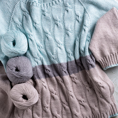 Beautiful classical casual turquoise gray women jumper with cables texture and balls yarn. Stylish...