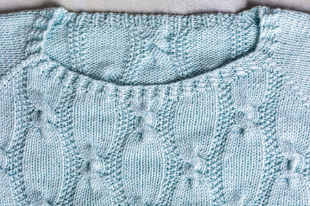 Background with turquoise knitting pattern for sweater with cables. Above overhead shot of neckline....