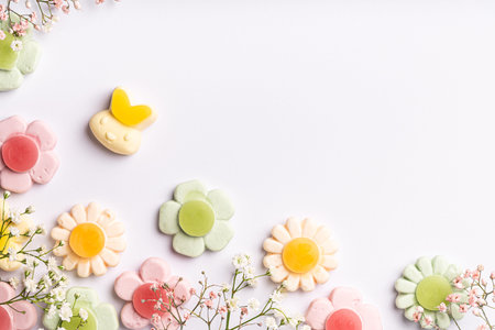 Assorted pastel flower-shaped gummy candies arranged on white background, creating a playful and...