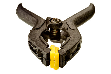One black plastic clamp with yellow tip on whiteの写真素材