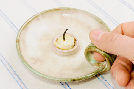 Old candlestick with burnt down candle, hand holding handleの写真素材