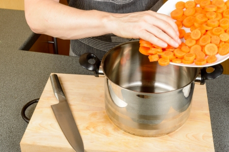 Pouring diced carrots from plate to panの写真素材