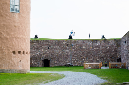 KALMAR, SWEDEN - APRIL 22, 2014: Girls taking pictures jumping of canon on castle wall.のeditorial素材