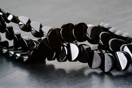 Strand of black quartz coin beads on stone plate.の写真素材