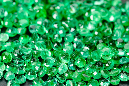 Large pile of green emeralds on black stone.の写真素材