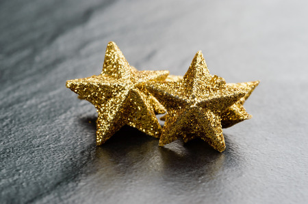 Golden sparkling glitter stars on black stone plate.の写真素材