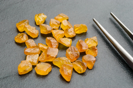 Yellow uncut, rough and raw sapphires with tweezers.の写真素材
