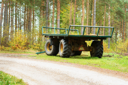 Green empty wagon standing in forest beside gravel road. Back and side view.の写真素材