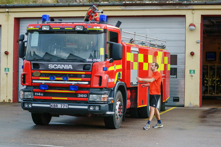 Ronneby, Sweden - October 26, 2014: Firefighter in shorts and tshirt walking to fire truck outside...