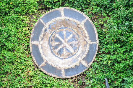 Ronneby, Sweden - October 26, 2014: Artistic object on ivy covered wall outdoors. Circular gray plate bathing in green ivy.のeditorial素材