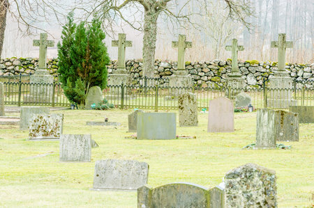 Five christian crosses on grave yard. Lots of tomb stones in foreground and fence in front of...