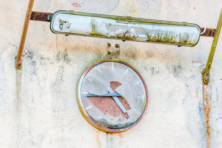 Old broken clock on industrial wall. Cover is broken and time has stopped. Place for text beside...