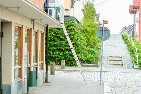 Karlshamn Sweden  May 06 2015: Unattended ladder placed on sidewalk against building. Air conditioner being fitted. Nobody in sight.のeditorial素材