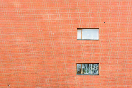 Huge brick wall on modern building with two windows. Reflections in windows. Copy space to the left.の写真素材