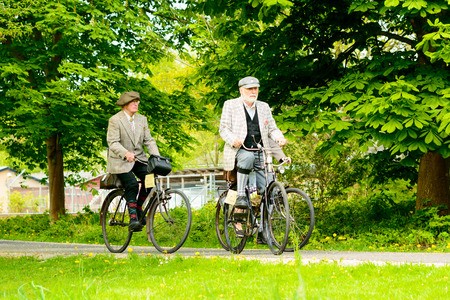 Solvesborg, Sweden - May 16, 2015: International Veteran Cycle Association (IVCA) 35th rally. Costume ride through public streets in town. Two men on old bikes.のeditorial素材