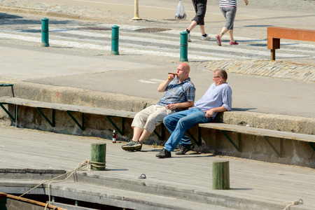 Ronneby, Sweden - June 13, 2015: Two unknown male persons sit on bench. One smoke cigar, both are relaxed.のeditorial素材