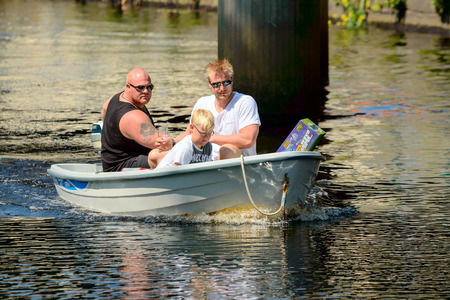 Ronneby, Sweden - June 13, 2015: Sillarodden, a public rowing contest from sea to town to sell herring. Three persons in small motor boat on the river seen face on.のeditorial素材