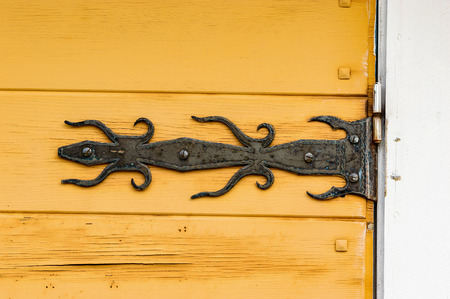 Black old iron hinge on old yellow wooden door.の写真素材