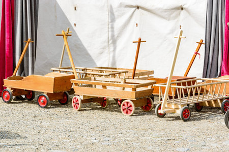 Childrens wooden toy carts parked outside a tent in the sunshine.