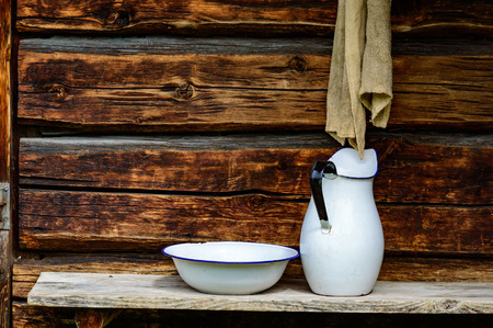 Place to wash up with white jug and bowl for water and a rugged cloth to dry with. Timber facade with copy space.の写真素材