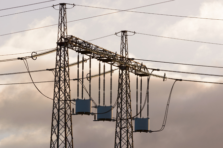 Line traps, also called wave traps, suspended under a high voltage power line pylon. Weather is clearing up after a storm and the early sunlight hits the traps ever so slightly.の写真素材