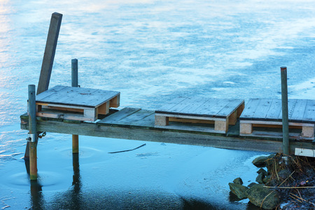 Small pallets on a wooden jetty surrounded by sea ice.の写真素材