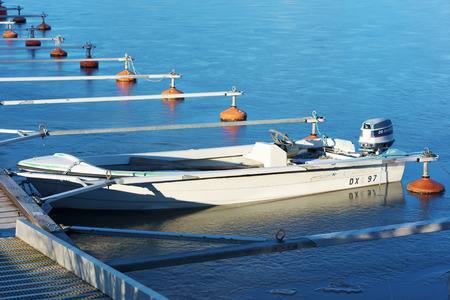 Karlskrona, Sweden - January 13, 2016: A small boat has been left in a marina and has frozen in the ice. It lies low in the ice. The small motor is also still on the boat.のeditorial素材