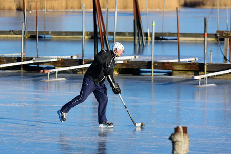 Listerby, Sweden - January 17, 2016: An unknown adult male is skating with a hockey stick in the...