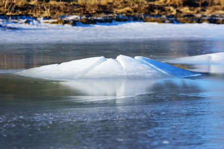 A granite boulder pushes through the ice surface as the ice level lowers. This forms a fine ice hill around the stone. A natural ice formation with beauty. Natural forces at play.の写真素材