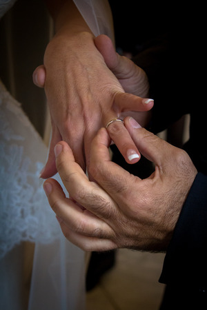 groom putting the ring on brideの写真素材
