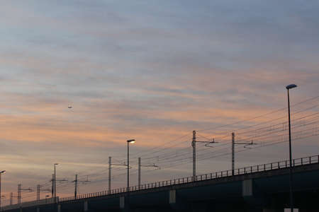 Silhouette of a bridge at sunset with clouds in the skyの写真素材