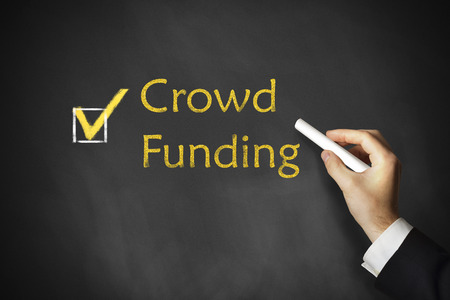 hand drawing a crowd funding on a chalk board wearing suiteの写真素材