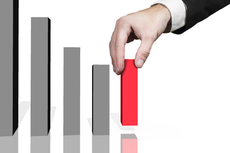 businessman picks up red domino block in raising row の写真素材