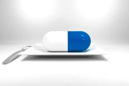 large sized blue pill on white plate with silver spoonの写真素材