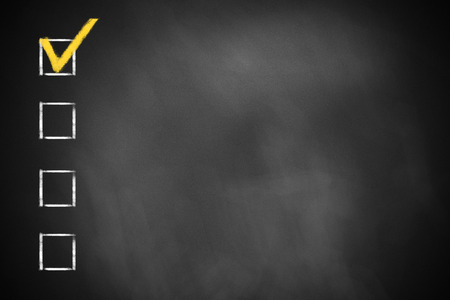 four checkboxes on a dark black chalkboardの写真素材