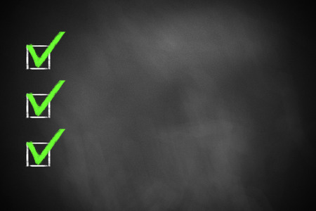 three green marked checkboxes on a black chalkboardの写真素材