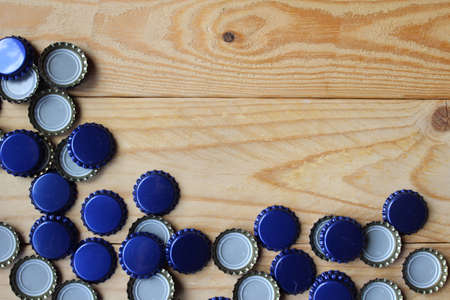 Flat lay view of blue beer bottle tops on a rustic wooden table. Home beer brewing concept with copy space .の写真素材