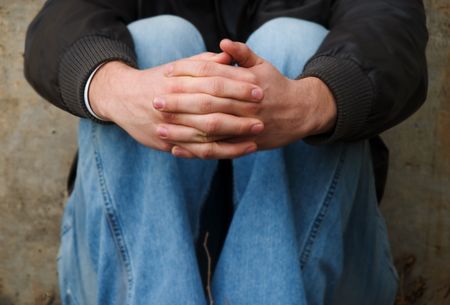 a homeless man sitting with his hands folded (rough look and contrast to give raw feel)の写真素材
