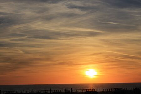 A beautiful scenery of the red horizon and cloudy sky captured during the sunsetの写真素材
