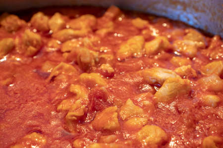 A pot full of chicken sauce, made with only the tomato sauce and the chicken pieces.の写真素材