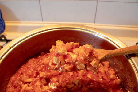 A pot full of chicken sauce, made with only the tomato sauce and the chicken pieces.の写真素材