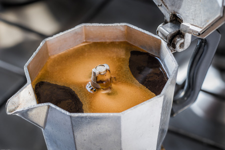 Italian traditional coffemaker with hot coffee flowing out from the spoutの写真素材