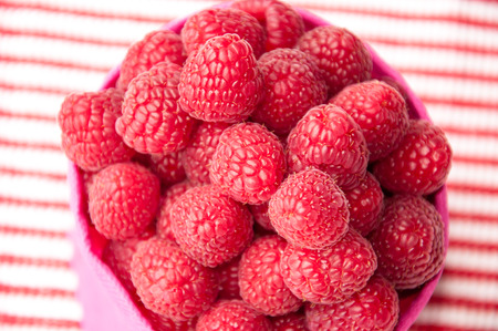 group of beautiful pink raspberries on a striped light background diagonal with a focus on the first layer of berriesの写真素材