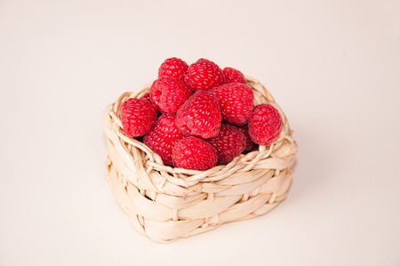 group of beautiful pink raspberries in a white basketの写真素材