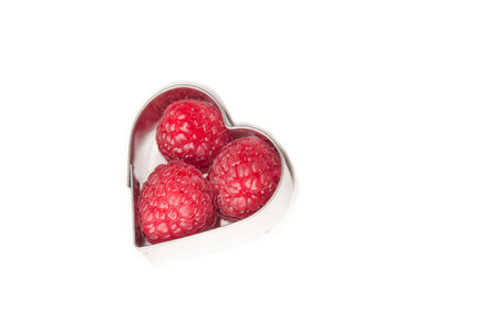 beautiful pink raspberries in a metal heart on a white backgroundの写真素材