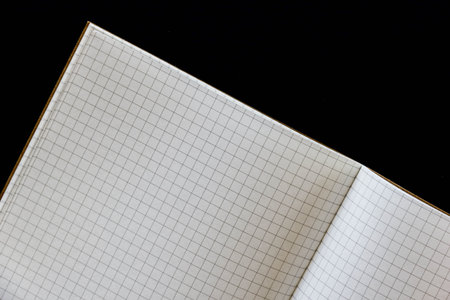 Squared paper notebook on black background, copy space